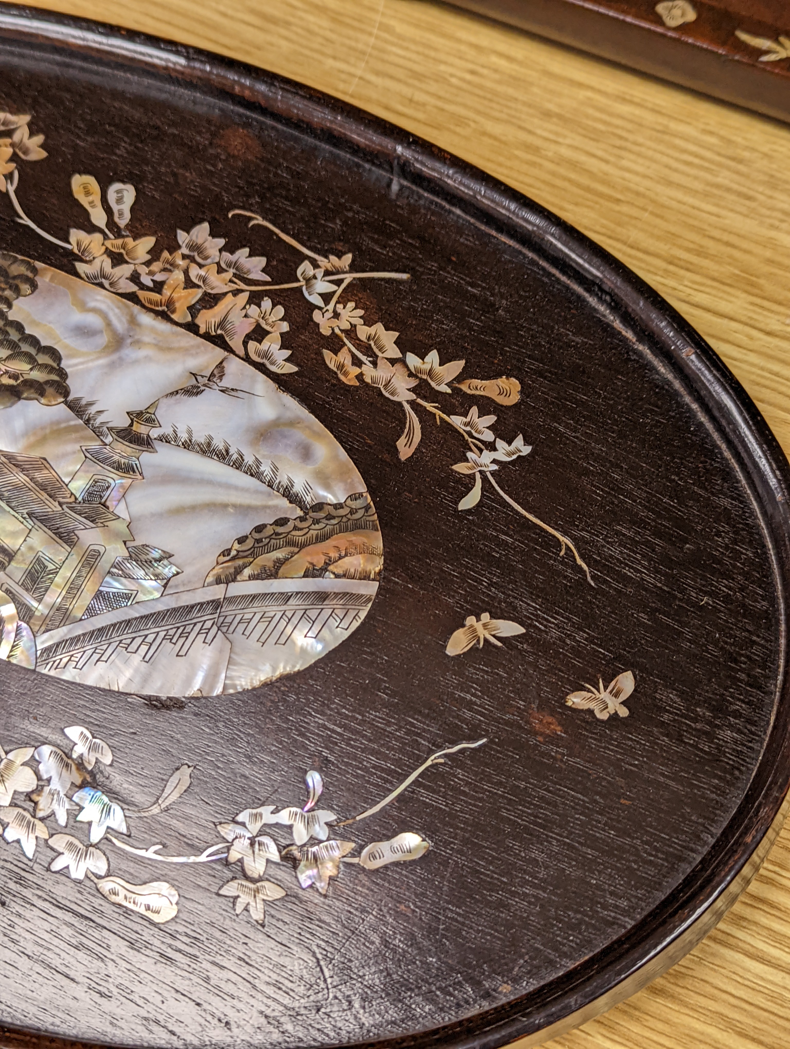 Two Chinese mother of pearl inlaid hongmu trays, the rectangular example with birds and insects amid flowers and the smaller oval example with a pavilion in a landscape within floral sprays 55x34cm
